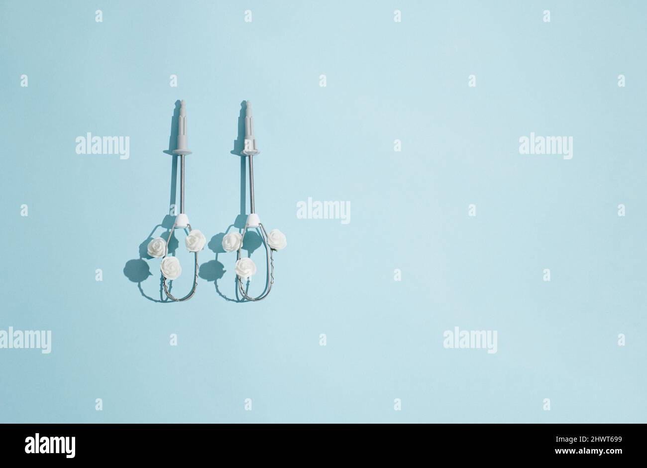 Creative concept made of electric egg beaters and white rose flowers on pastel blue background. Minimal spring cooking idea. Flat lay top view composi Stock Photo