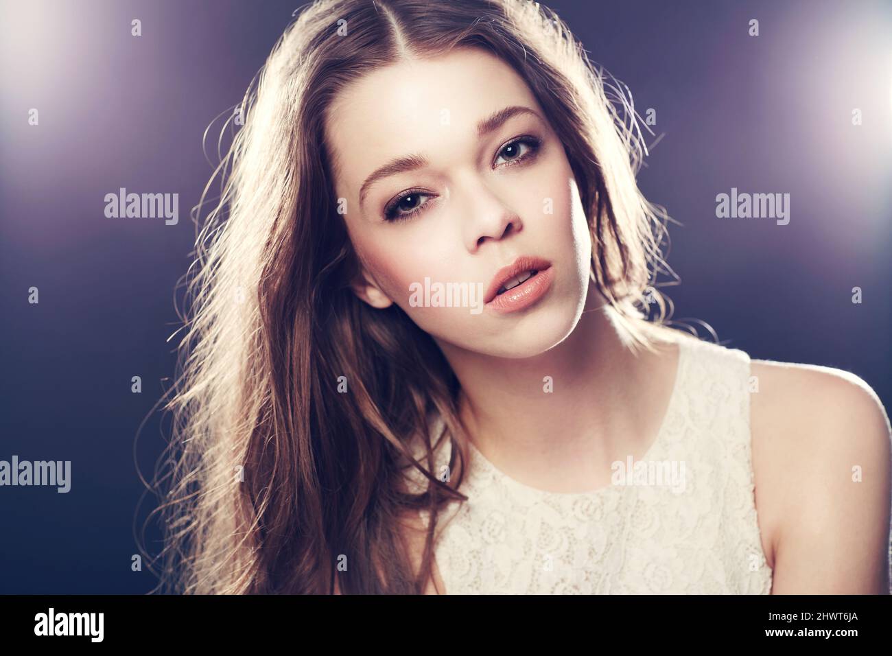 Stunning model in the limelight. A gorgeous young woman backlit with bright lights while isolated on black. Stock Photo