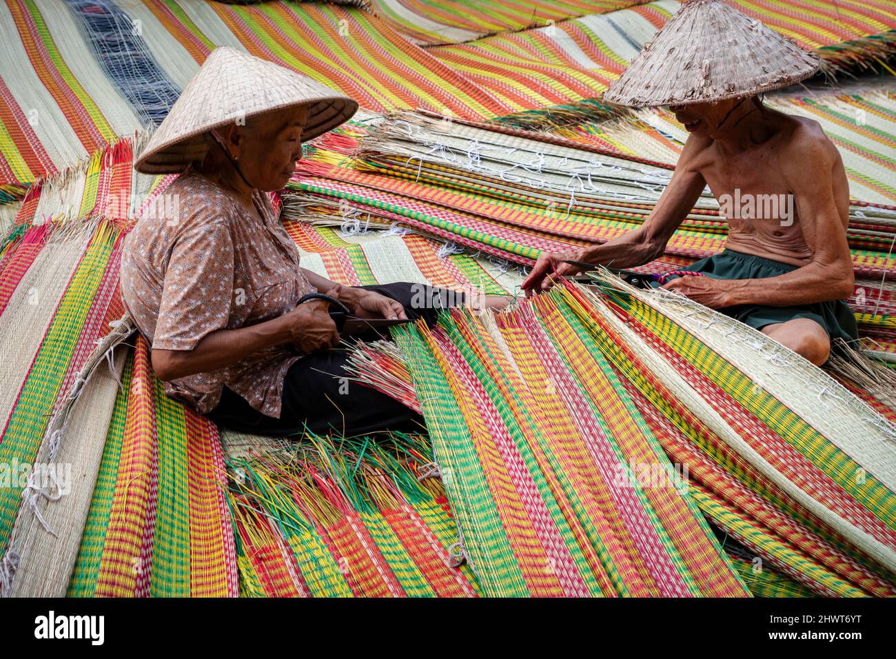Vietnamese Old Man and Women Making a drying traditional vietnam mats