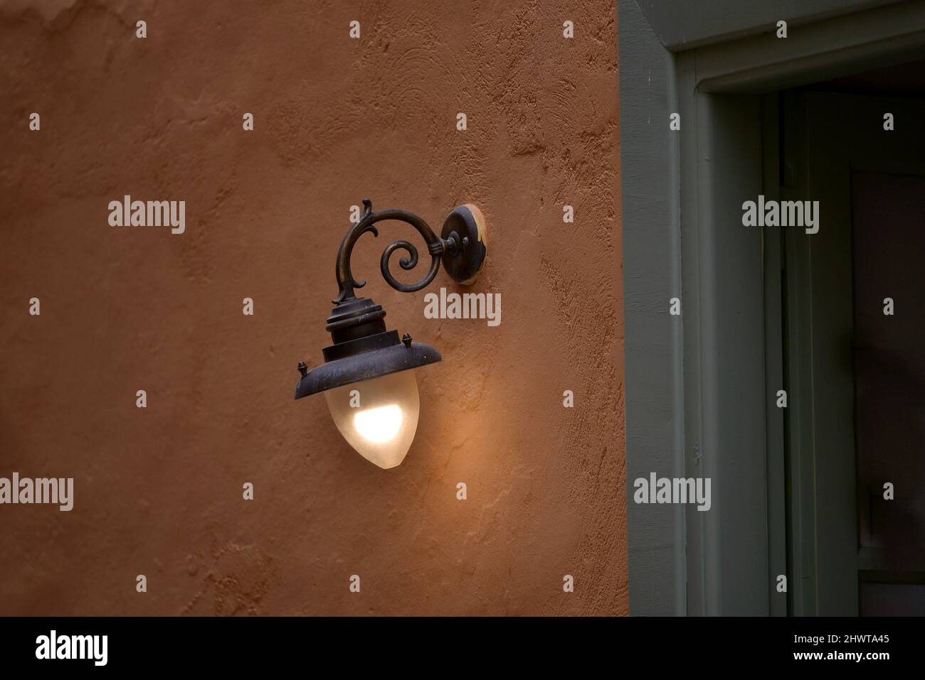 Antique handcrafted cast iron wall lamp against a stucco wall