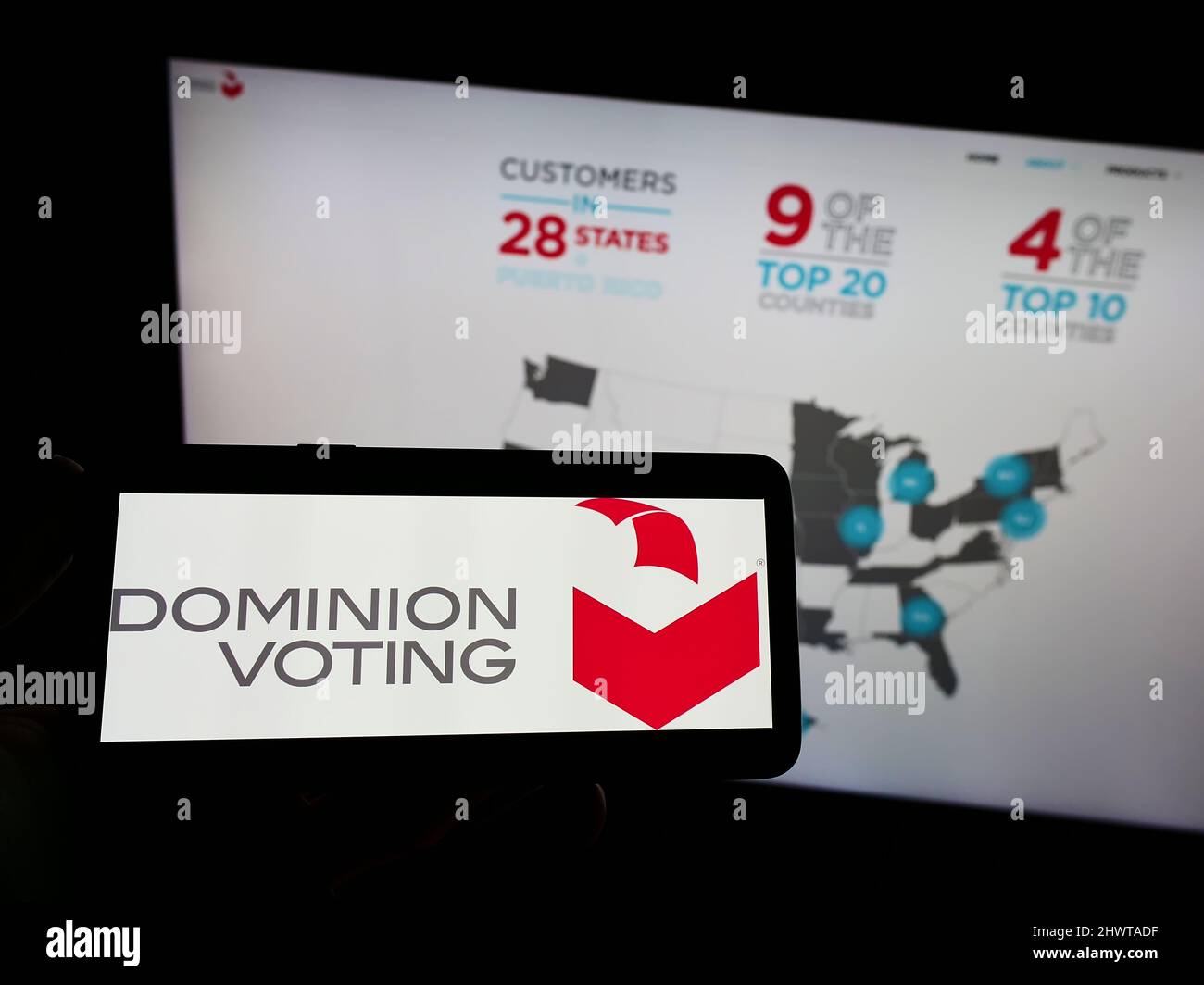 Person holding mobile phone with logo of company Dominion Voting