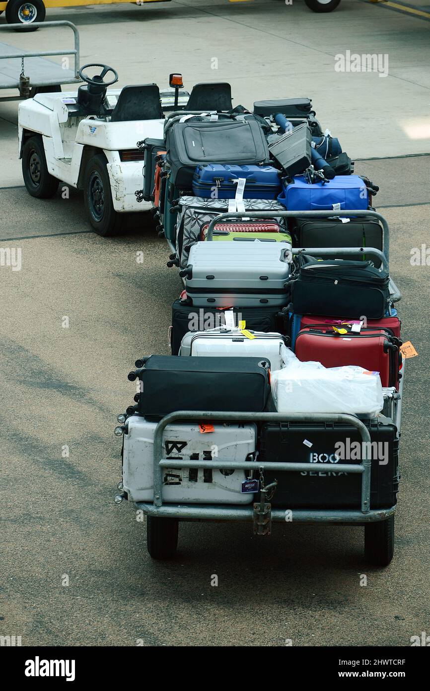 Baggage Handler loading and unloading baggage onto commercial airliner on a busy airport Stock Photo