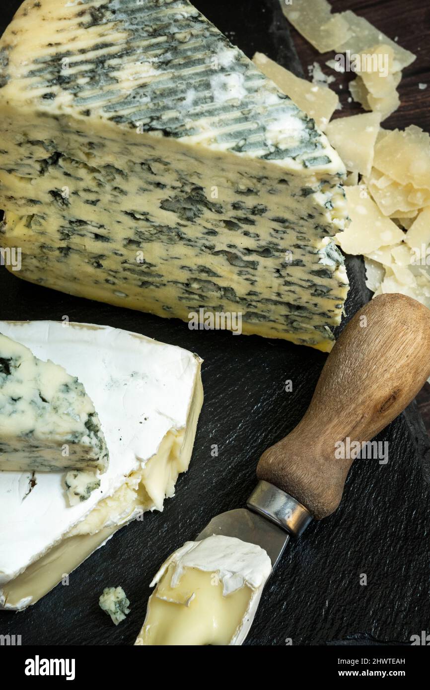 Small cheese knife with a piece of delicious brie next to a large taco of dairy cow blue cheese Stock Photo