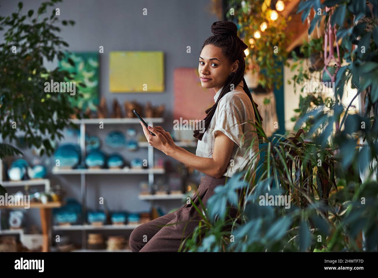 Tranquil floral designer using her cellphone at work Stock Photo