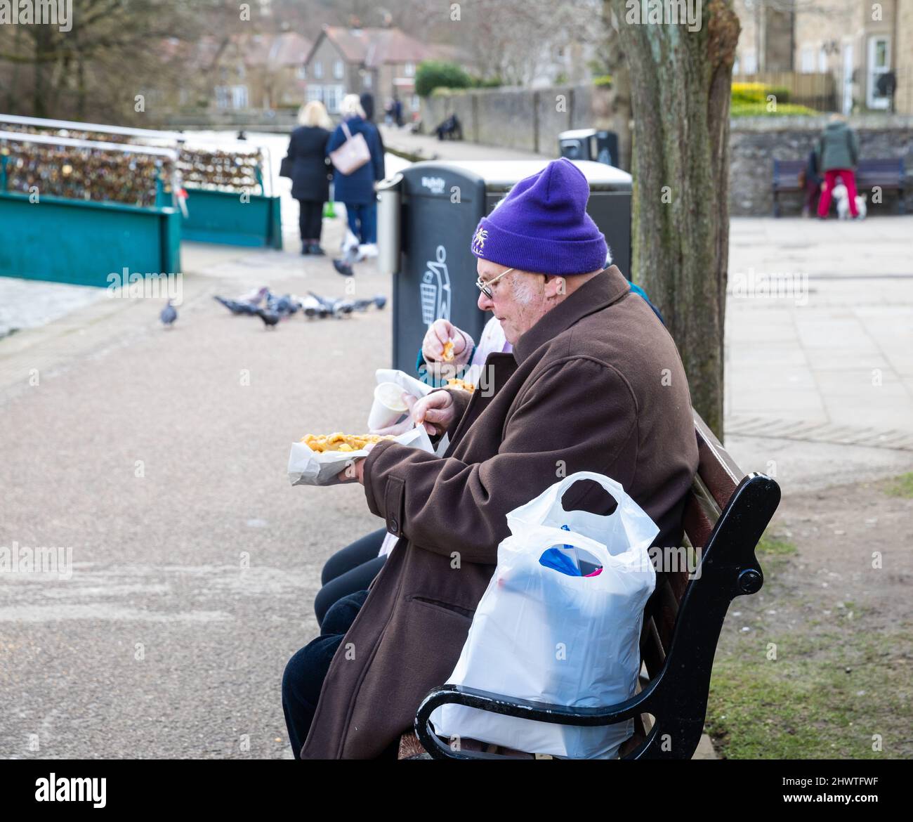 Bakewell, UK,2nd March 2022,An elderly couple sat eating Fish and Chips by the River Wye on Market Day which was very busy in Bakewell, Derbyshire despite being a chilly day. The forecast was for sunshine, 6C and a gentle breeze.Credit: Keith Larby/Alamy Live News Stock Photo