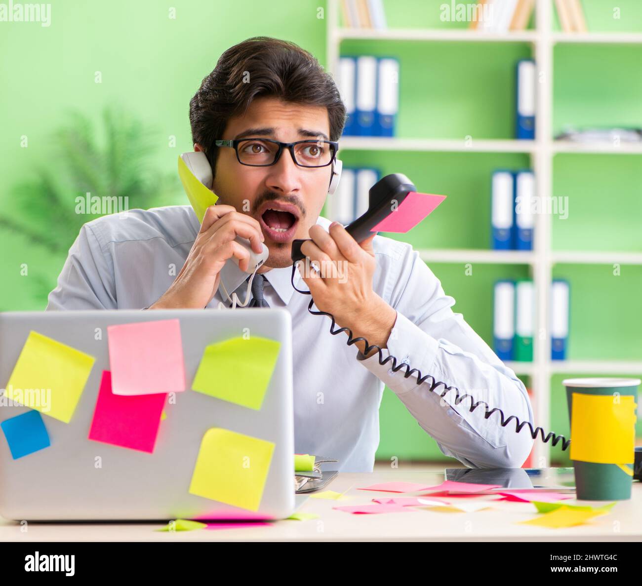 Young help desk operator working in office with many conflicting