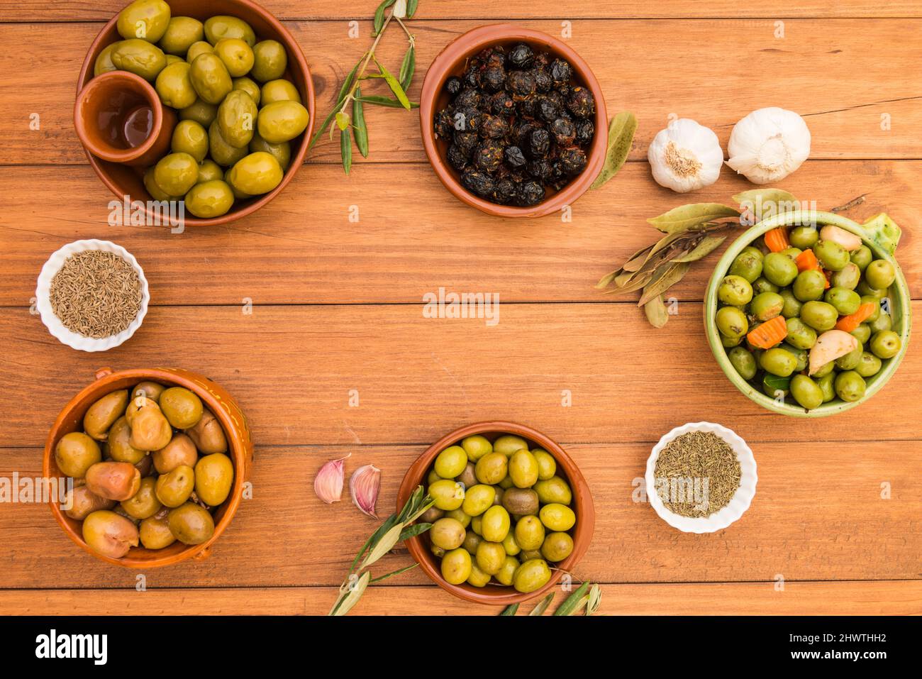Still life with different varieties of olives, presented in bowls on wooden boards, seasoned with different traditional dressings. Traditional homemad Stock Photo