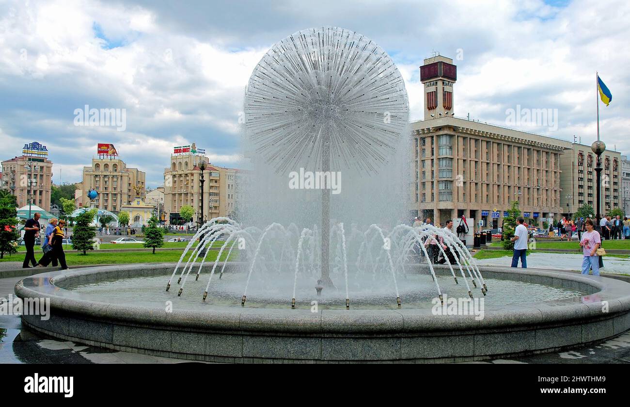 Kyiv or Kiev, Ukraine: Maidan Square or Independence Square in central Kyiv. View of a fountain with people. Buildings and the Ukrainian flag behind. Stock Photo