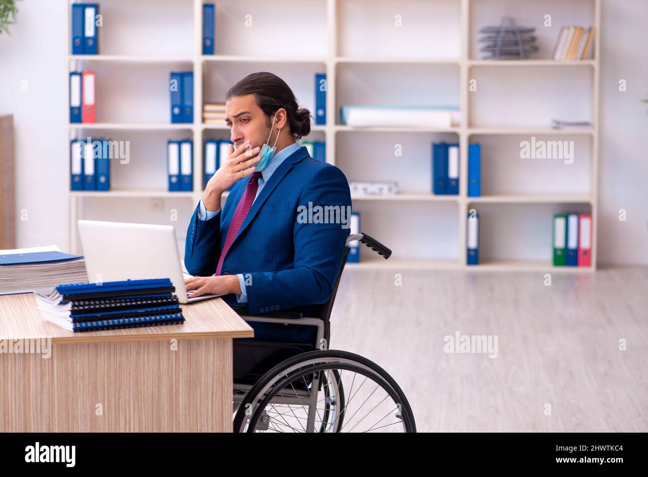 Young male disabled employee during pandemic at workplace Stock Photo ...