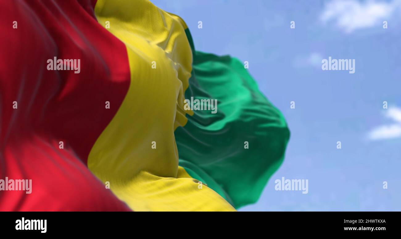 Detail of the national flag of Guinea waving in the wind on a clear day. Guinea is a coastal country in West Africa. Selective focus. Stock Photo