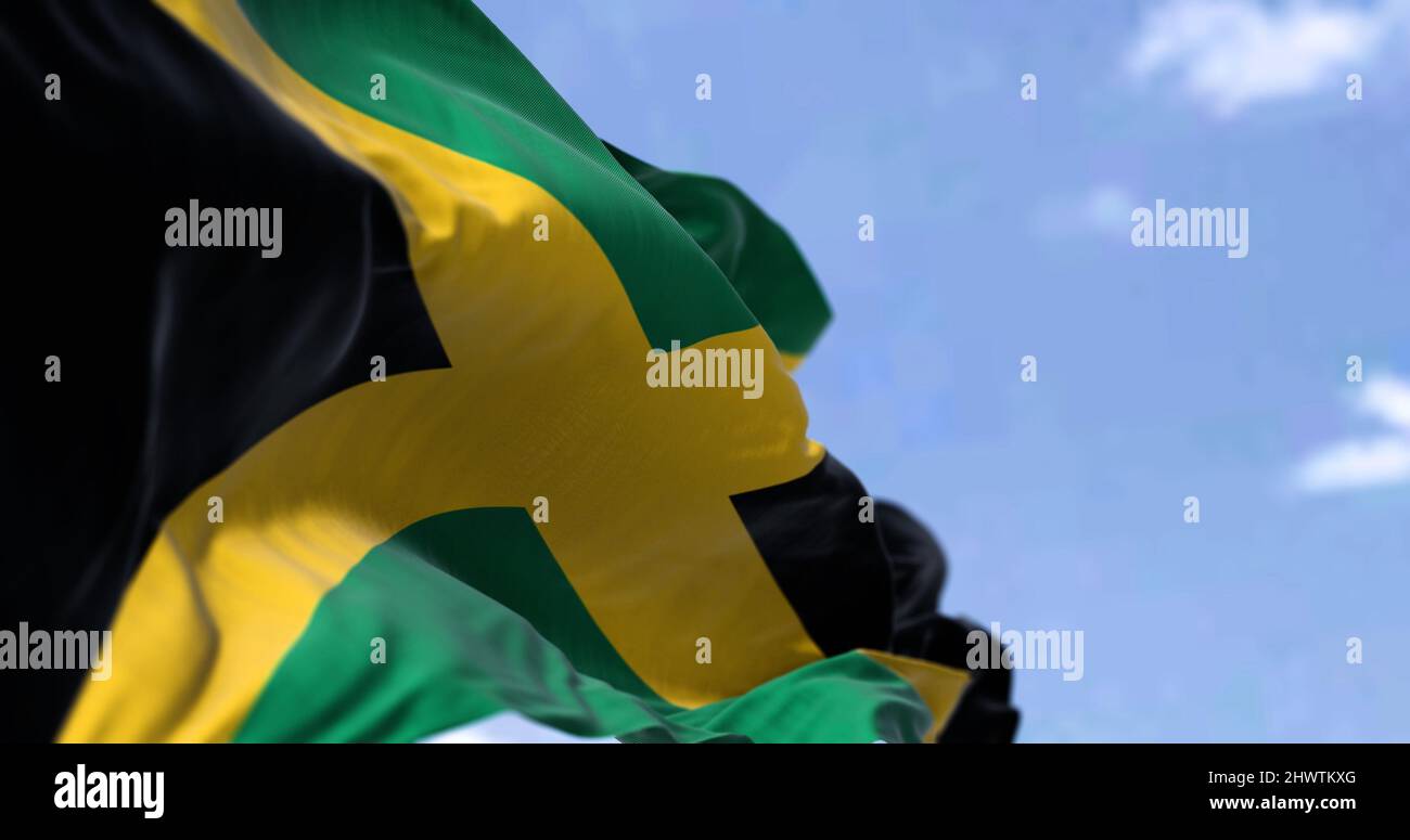 Detail of the national flag of Jamaica waving in the wind on a clear day. Jamaica is an island country situated in the Caribbean Sea. Selective focus. Stock Photo