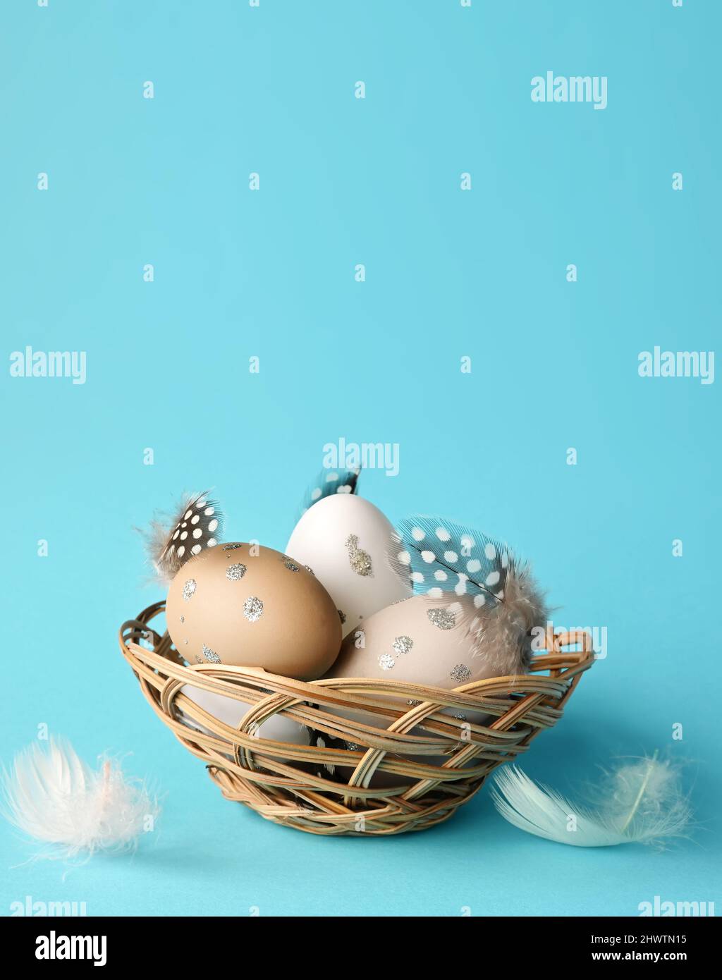 Easter eggs in a nest with feathers on a blue background. Holiday ...