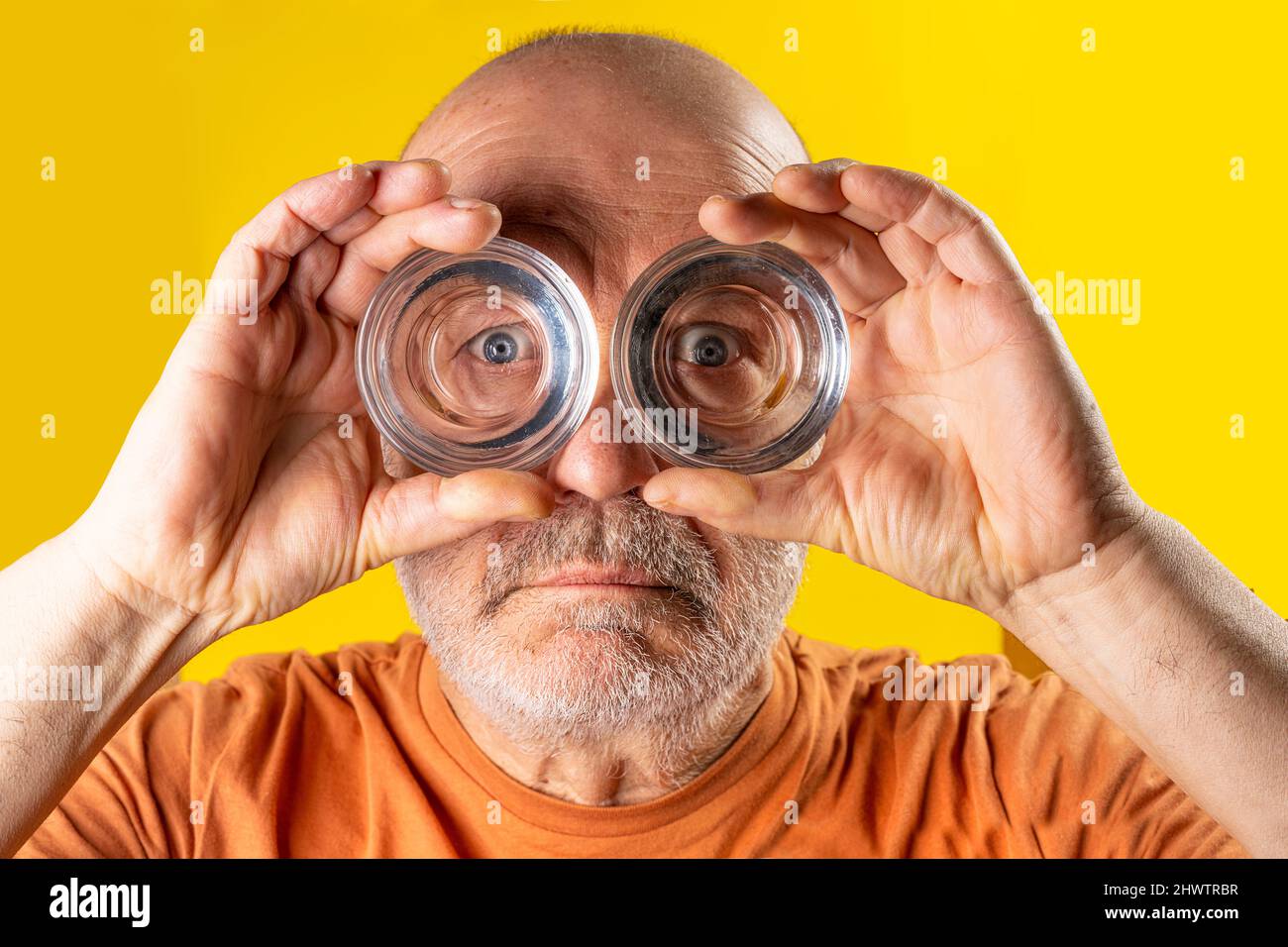 A man looking through the bottoms of glasses like binoculars Stock Photo