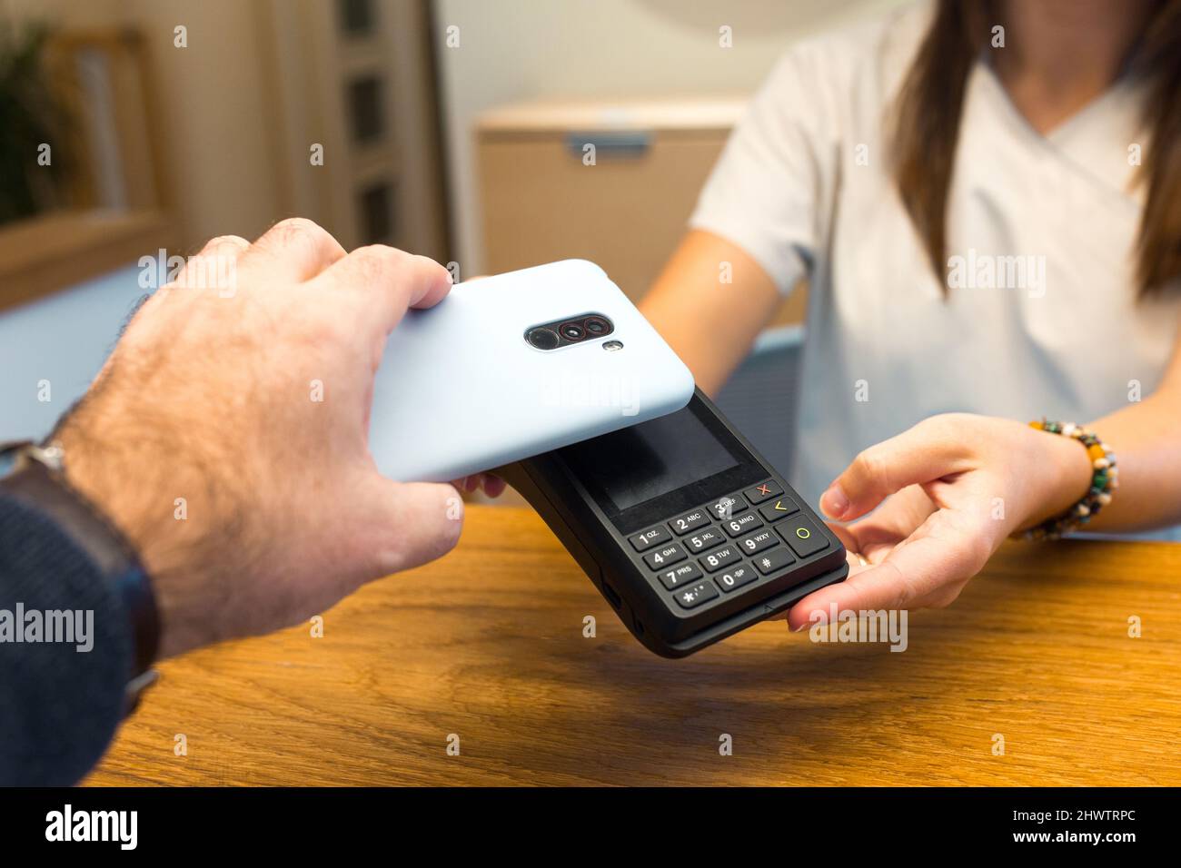 Man using smartphone for payment through terminal Stock Photo