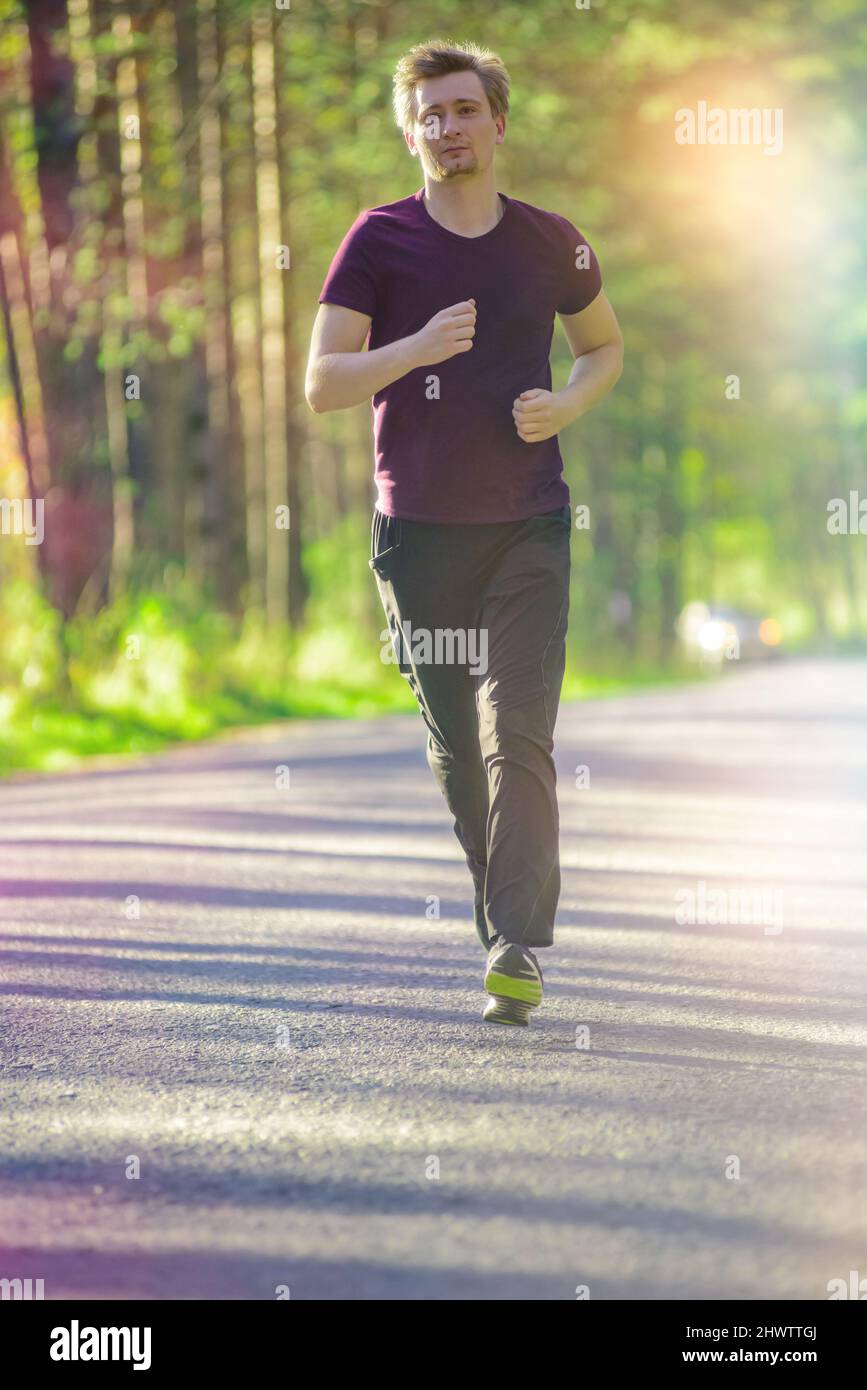 Running man jogging in city park at beautiful summer day. Sport fitness