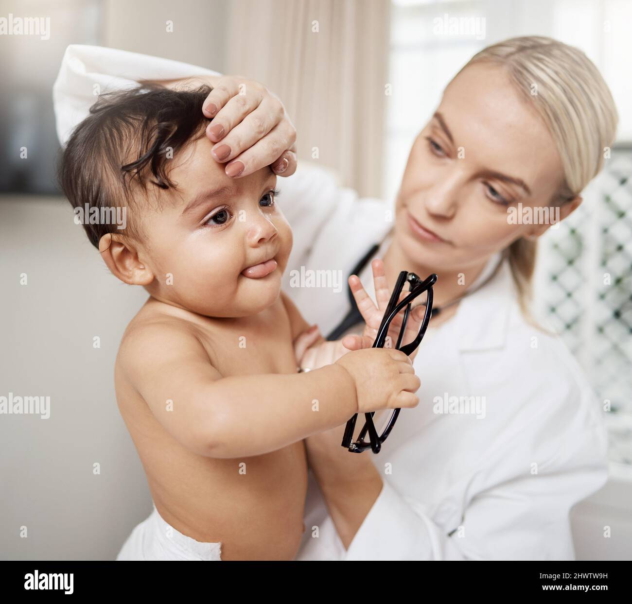 She definitely have a fever. Shot of a paediatrician taking a babys temperature. Stock Photo