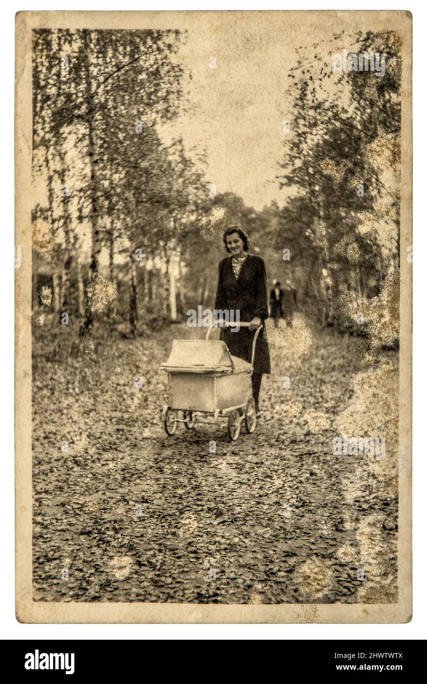 Old family photo. Mother with baby in vintage buggy. Nostalgic grungy picture with film grain Stock Photo