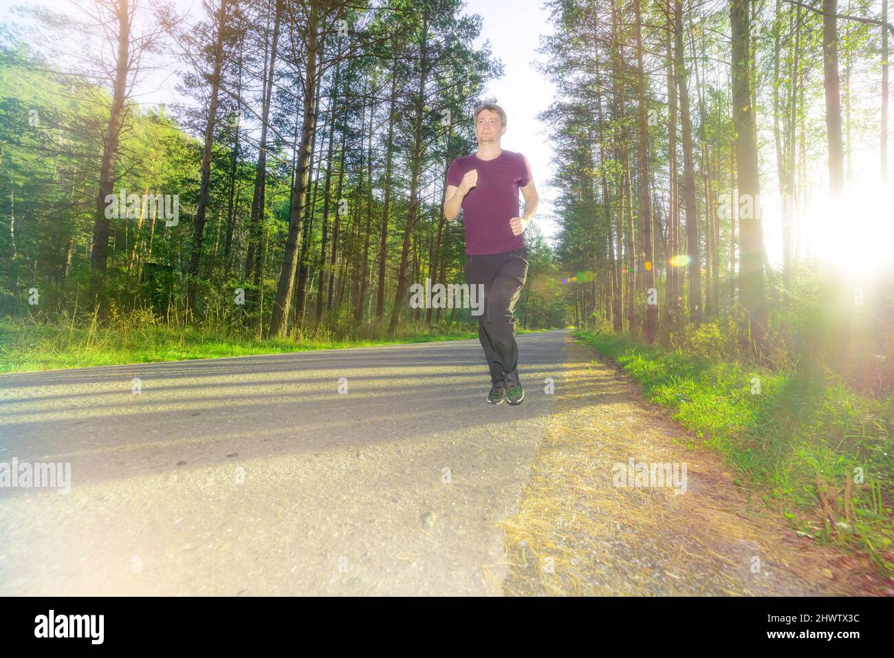 Running man jogging in city park at beautiful summer day. Sport fitness