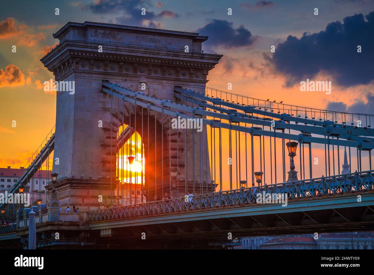 The famous Szechenyi Chain Bridge in Budapest above the Danube river, with sky illuminated by sunset, Hungary, Europe. Stock Photo