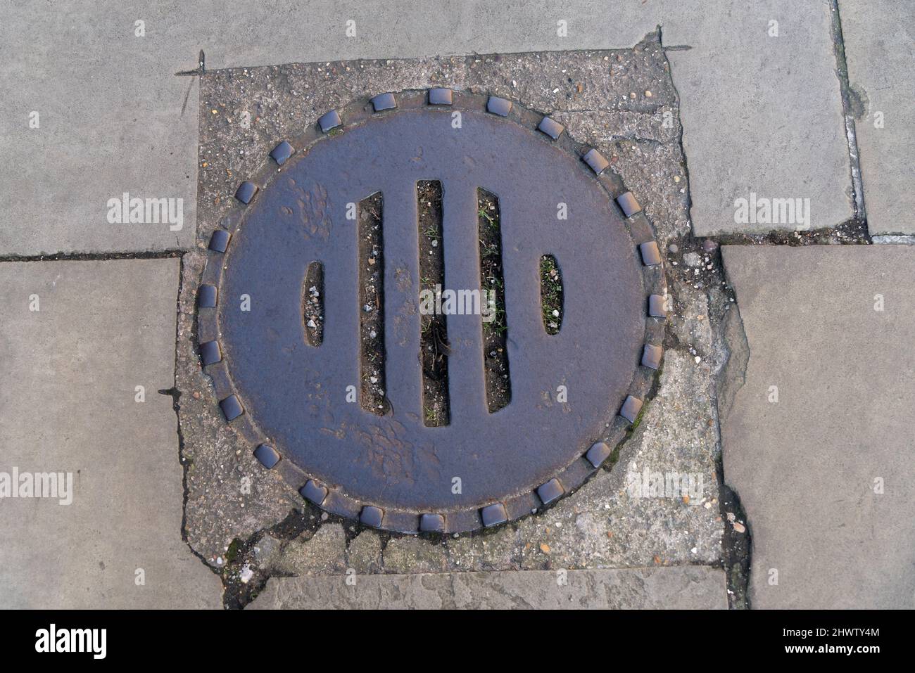 Drainage cover, manhole cover, cast iron cover, blocked drain, road drain, requires maintenance, sewers, combined system, curtilage, Victorian round. Stock Photo