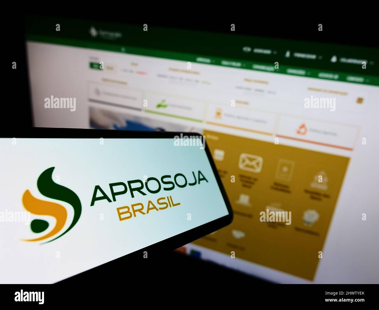 Mobile phone with logo of Brazilian agriculture company Aprosoja on screen in front of business website. Focus on center-left of phone display. Stock Photo