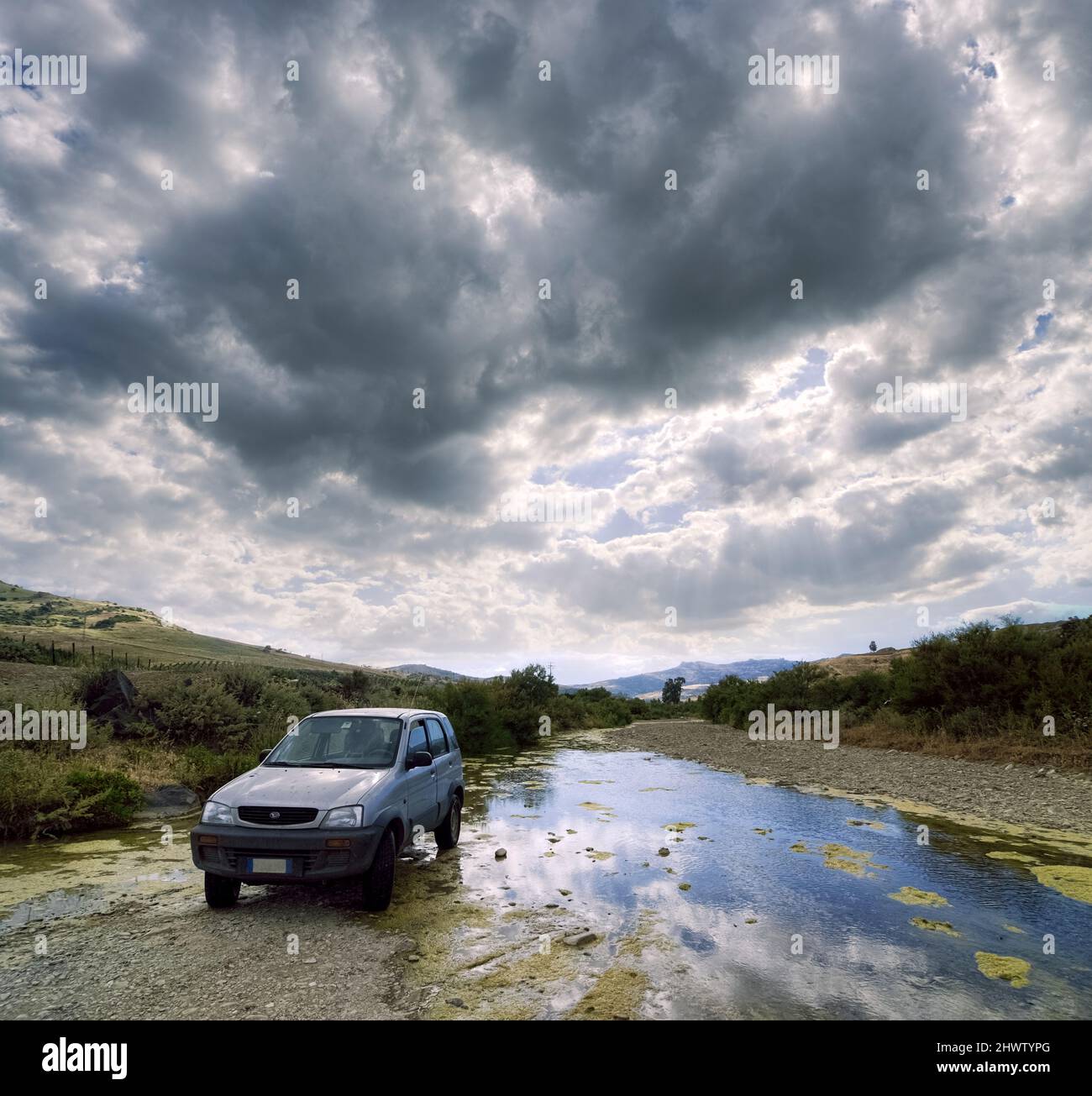 old car 4wd in off road against river and dramatic sky Stock Photo