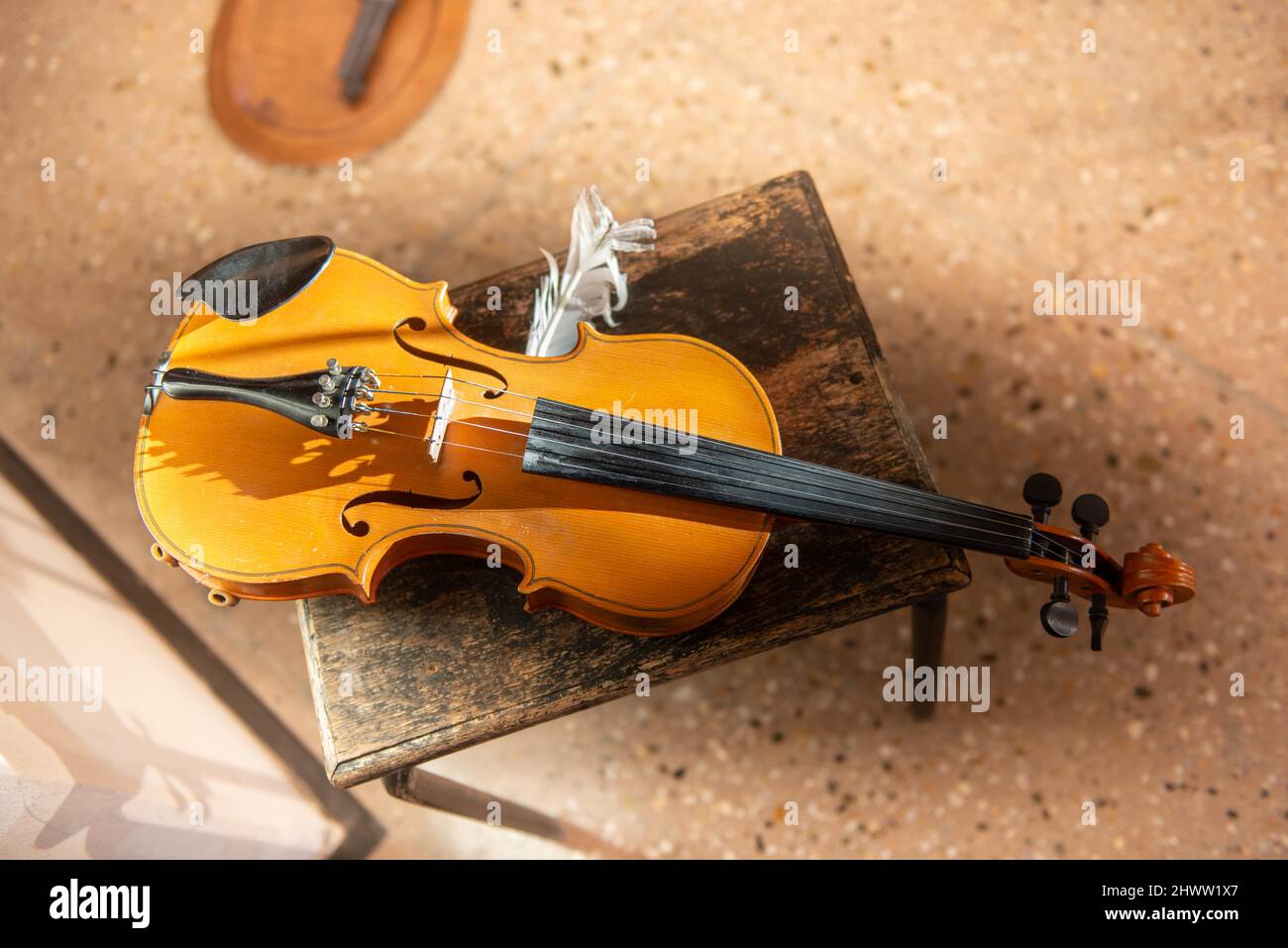 Violin with feather resting on stool Stock Photo
