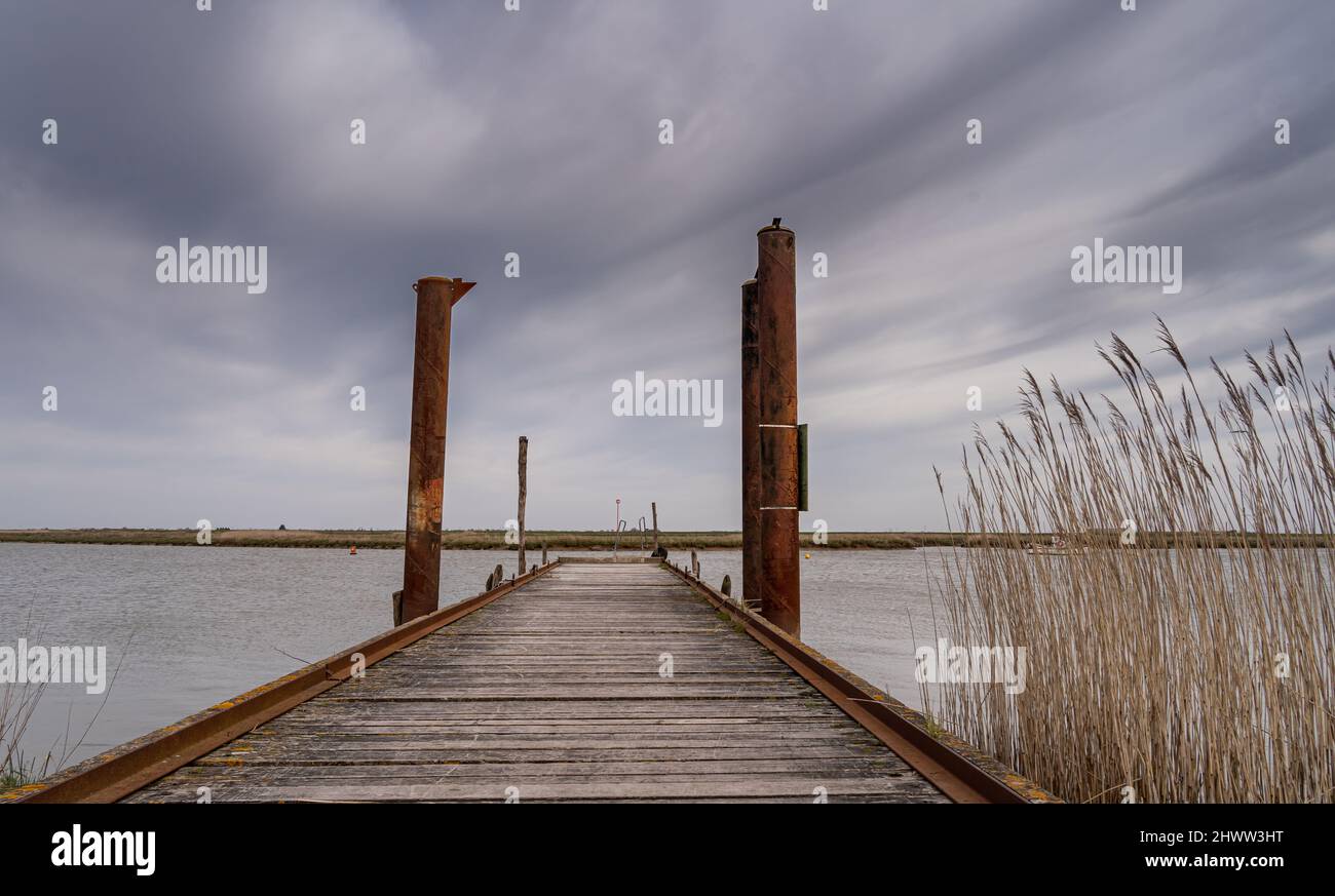 Long exposure of pier in calm lake, with nature all around, water is silky smooth. solitude concept Stock Photo