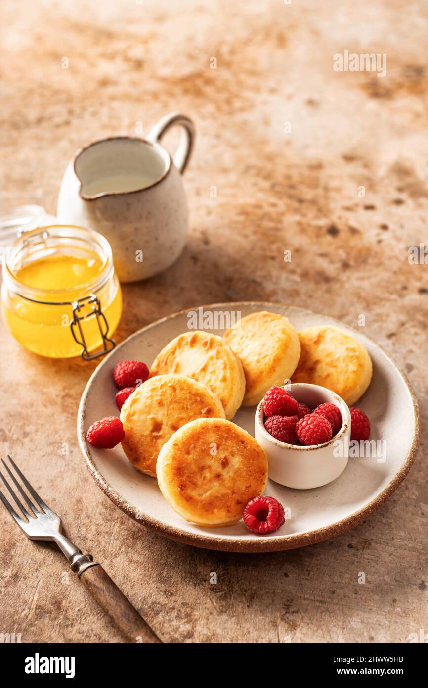Cottage cheese pancakes syrniki with fresh raspberry on textured background Stock Photo