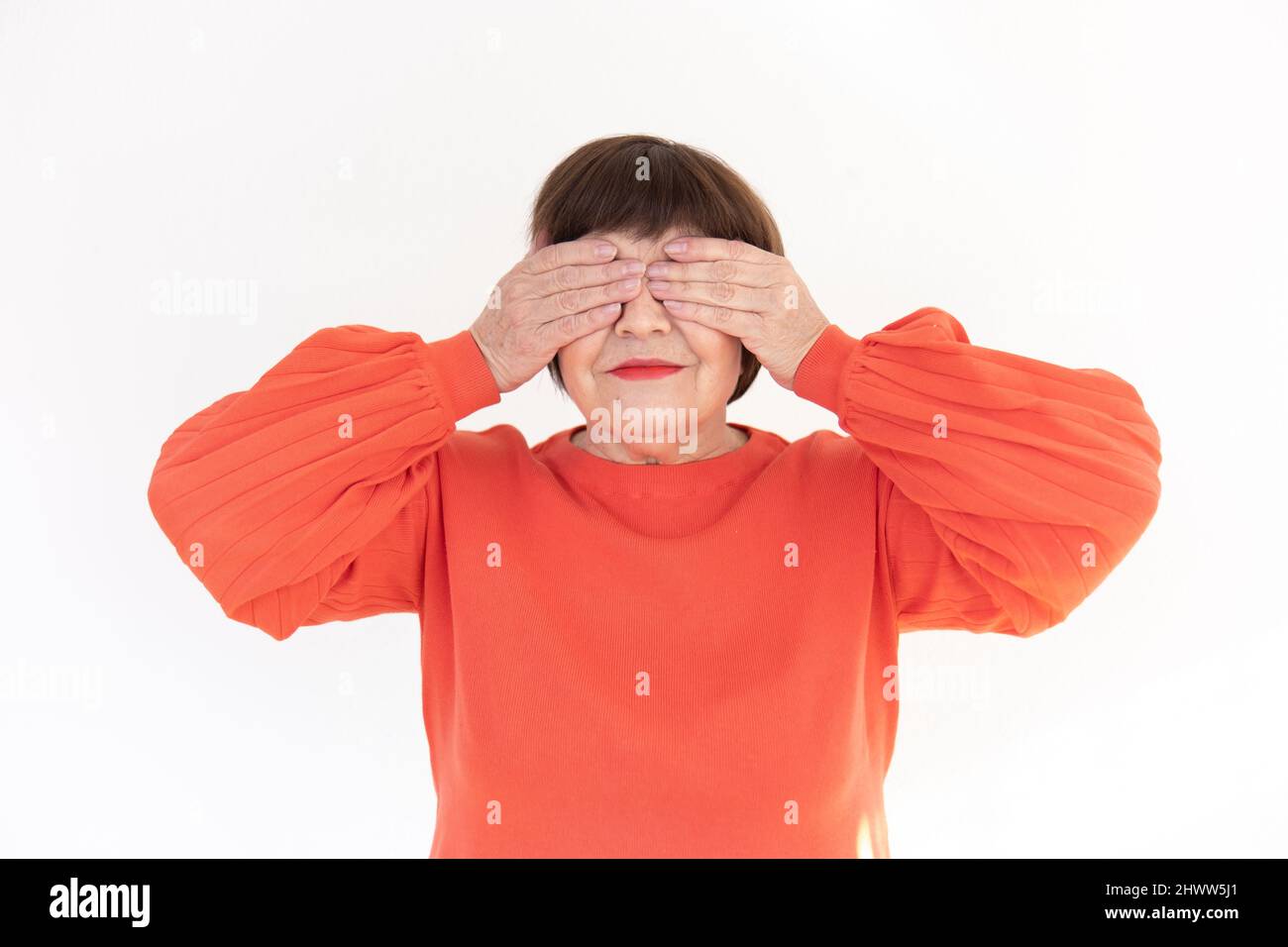 Old brunette woman making the see no gesture from the three wise monkeys - studio photo Stock Photo