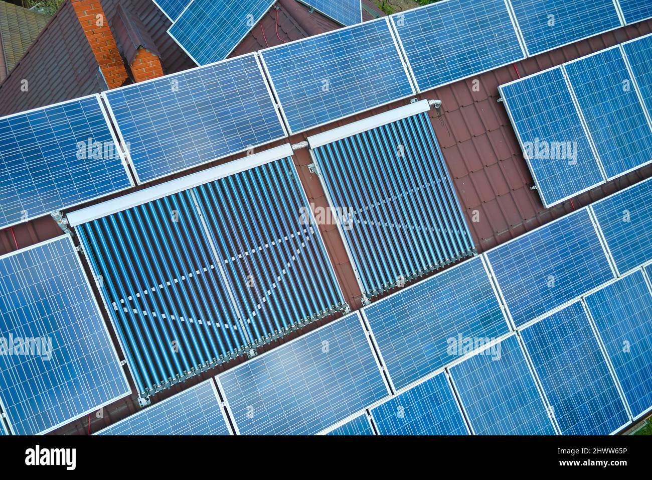Building roof with rows of blue photovoltaic panels and vacuum air ...