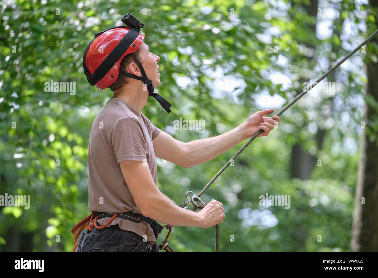 Man belays his partner climber with belaying device and rope. Climber's