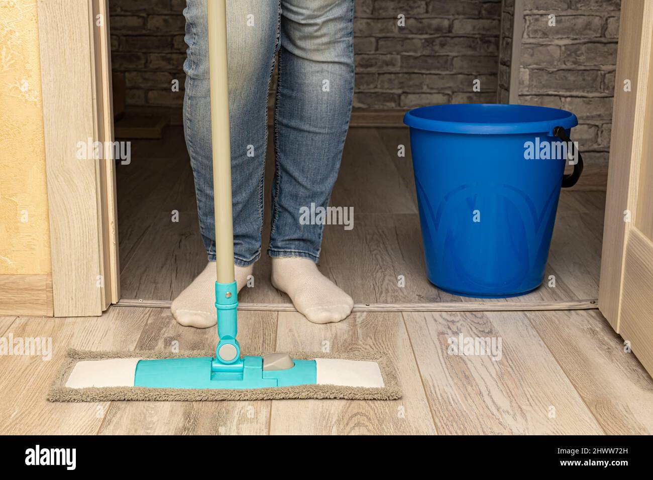 a man stands with a mop and a bucket at the door Stock Photo