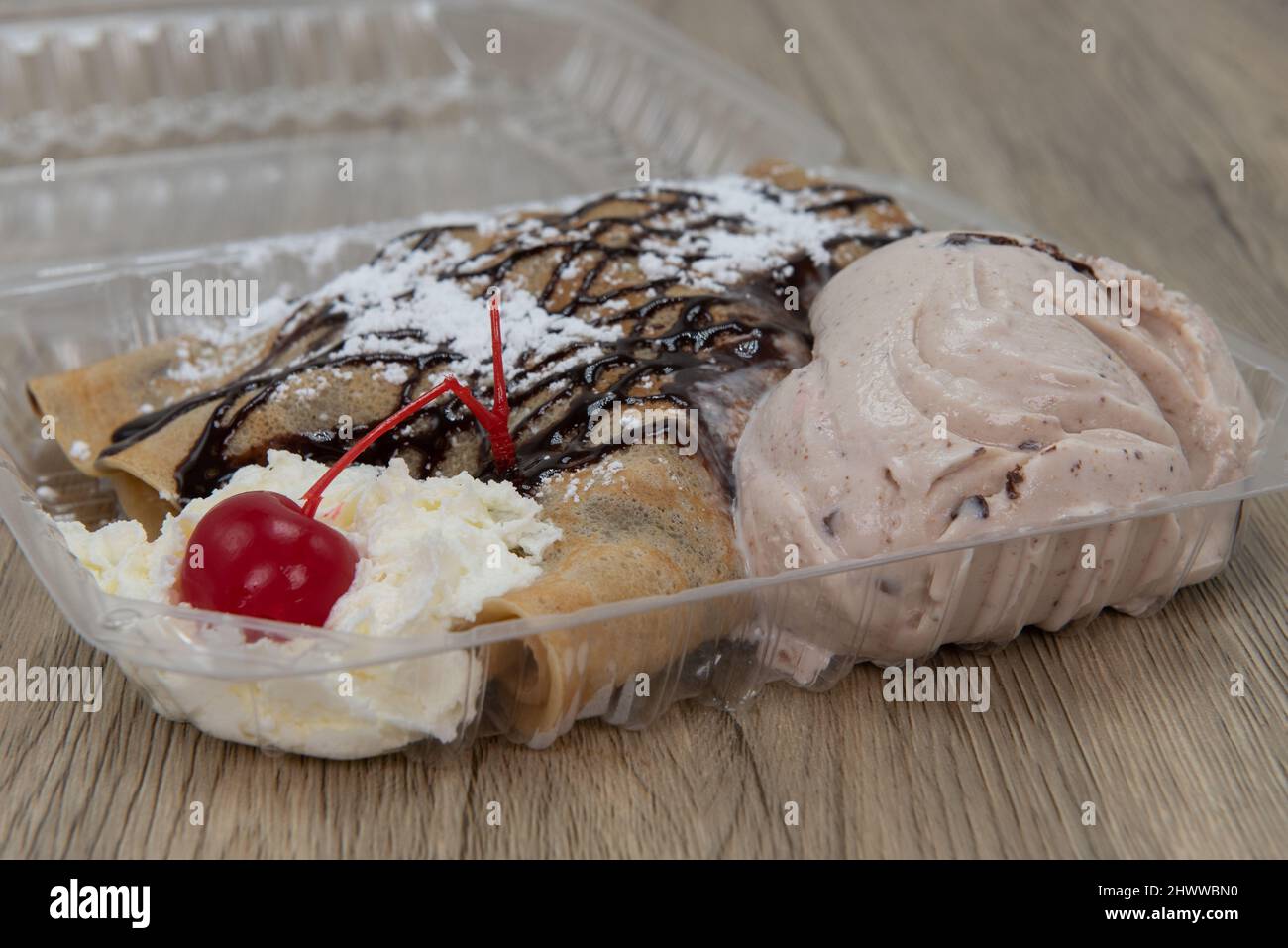 Hearty take out order of chocolate covered crepes, sprinkled with powdered sugar and whipped cream and served with ice cream. Stock Photo