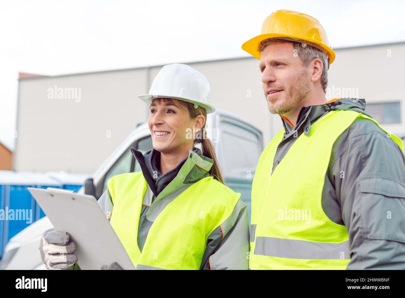 Workers with clipboards standing in front of small truck Stock Photo