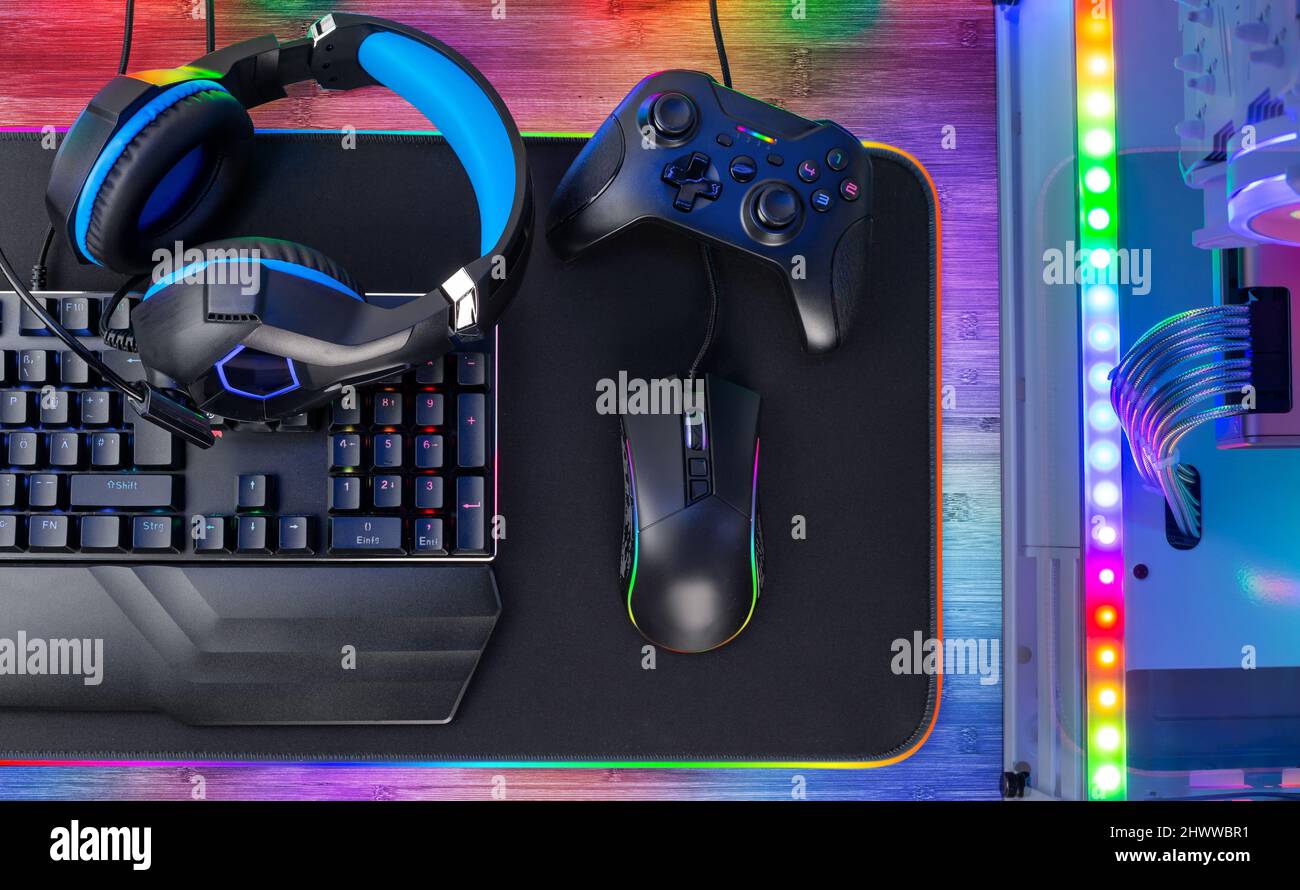 Top view of a colorful bright pc rgb LED gaming desk with headset keyboard mouse and desktop computer.  esports technology concept background Stock Photo