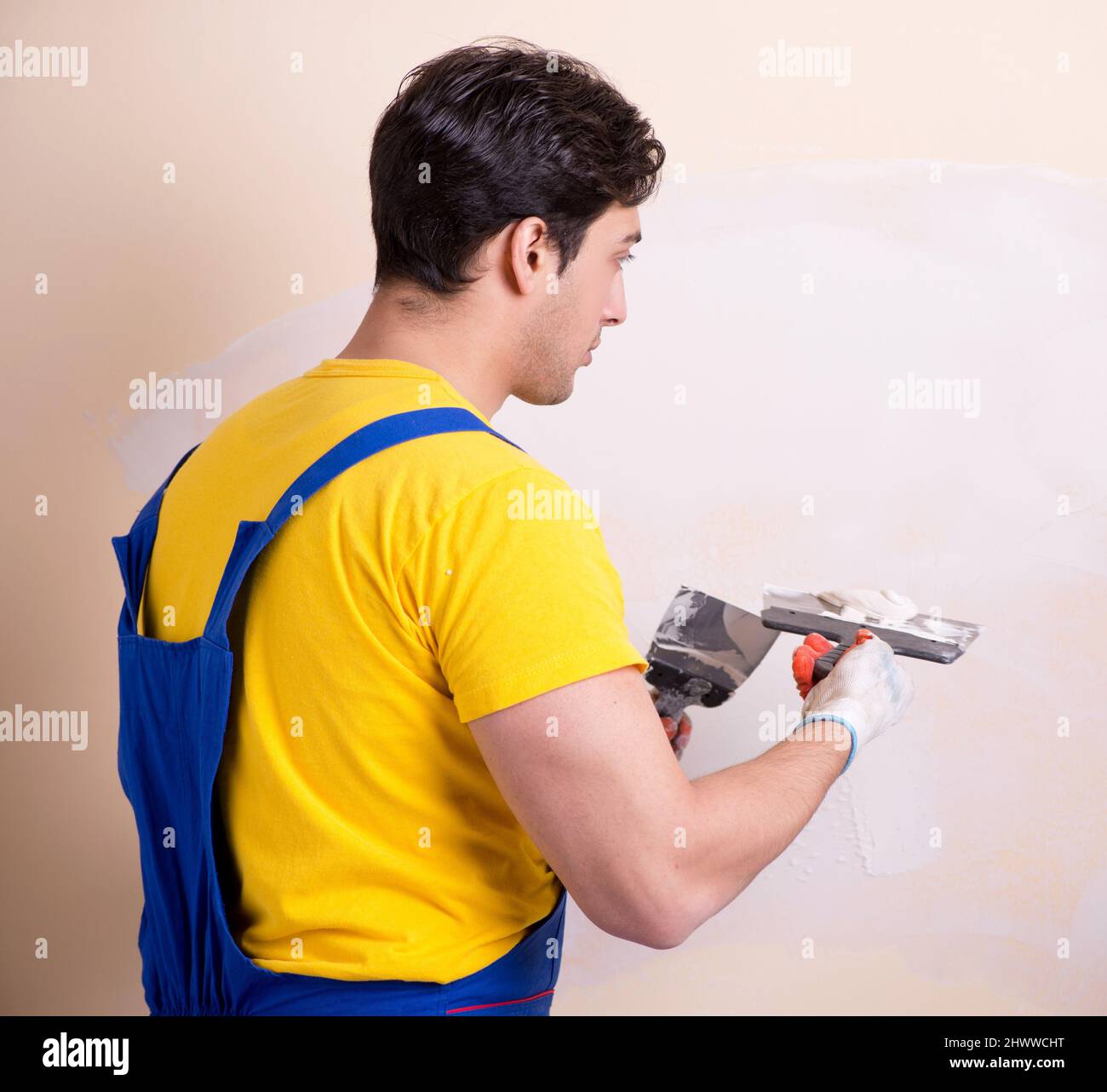The young contractor employee applying plaster on wall Stock Photo