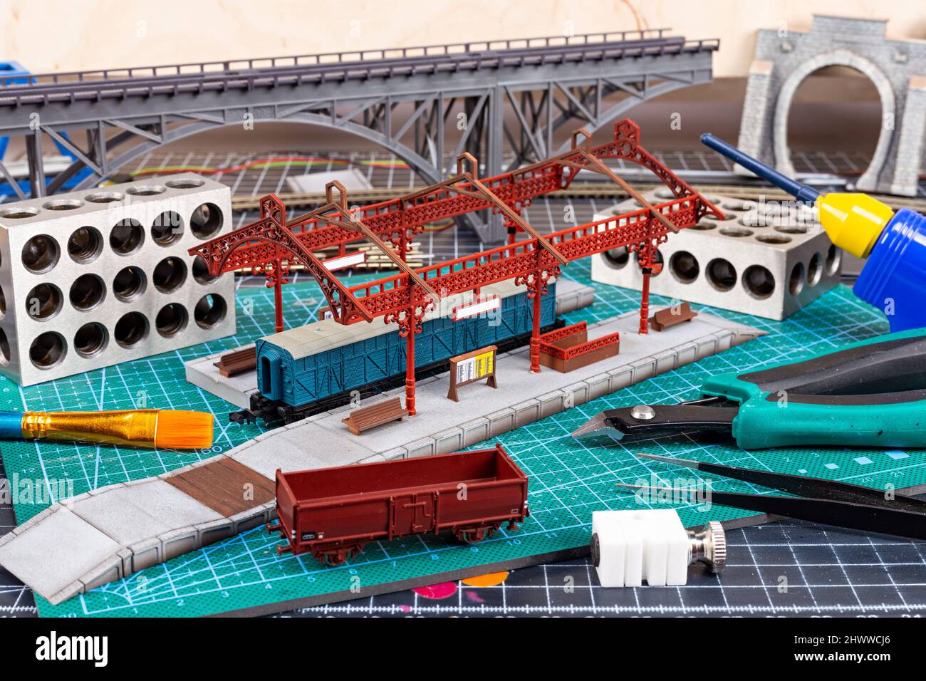 construction of a model railroad layout. workbench with model railway train station bridge tracks and landscape tools. hobby leisure scale modelling c Stock Photo