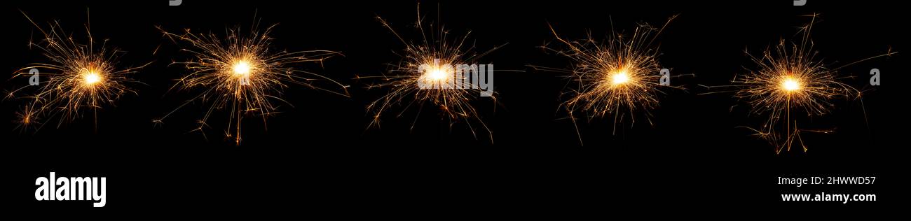 golden bright sparkler set collection in a panorama row new year symbol isolated on dark black background. silvester birthday wedding and celebration Stock Photo