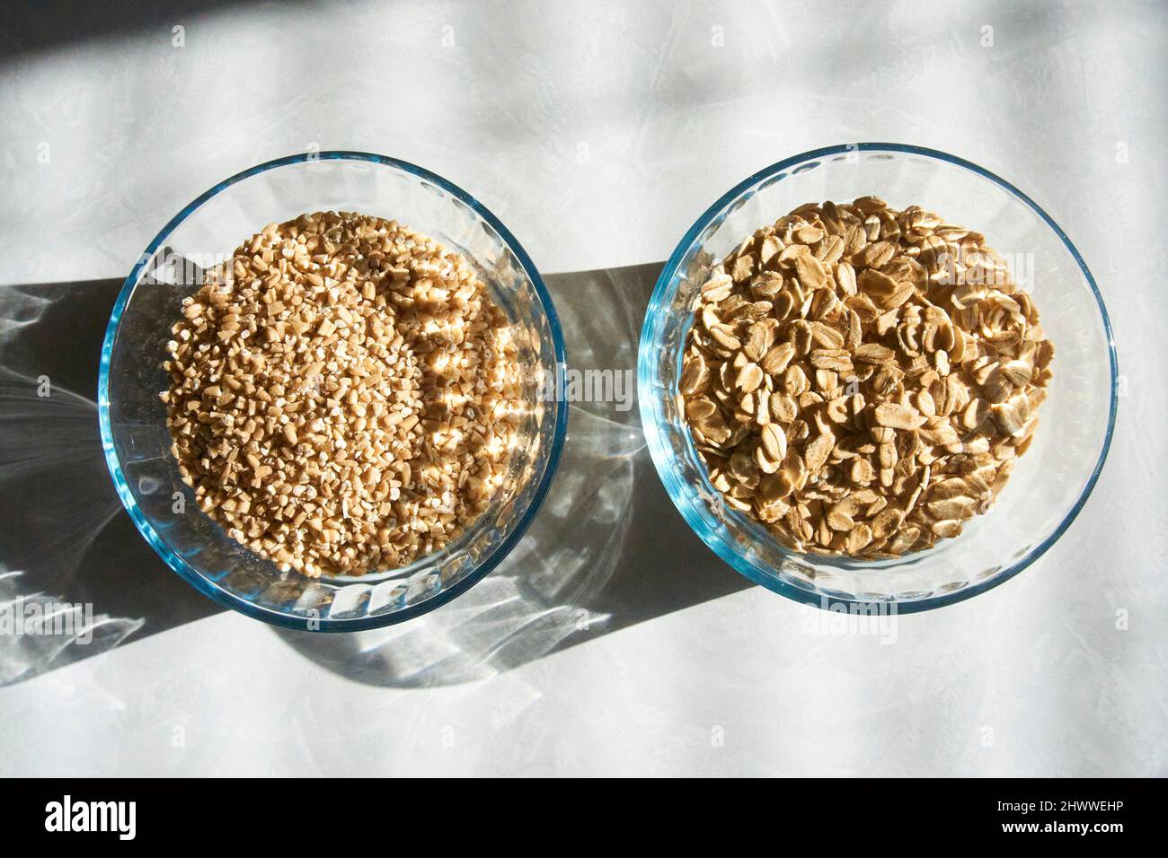 Two glass bowls of whole grain oats and steel cut oats. Stock Photo