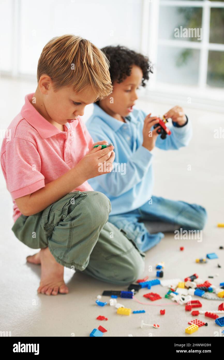 How do these pieces fit together. Two cute young boys playing with building blocks on the flor. Stock Photo