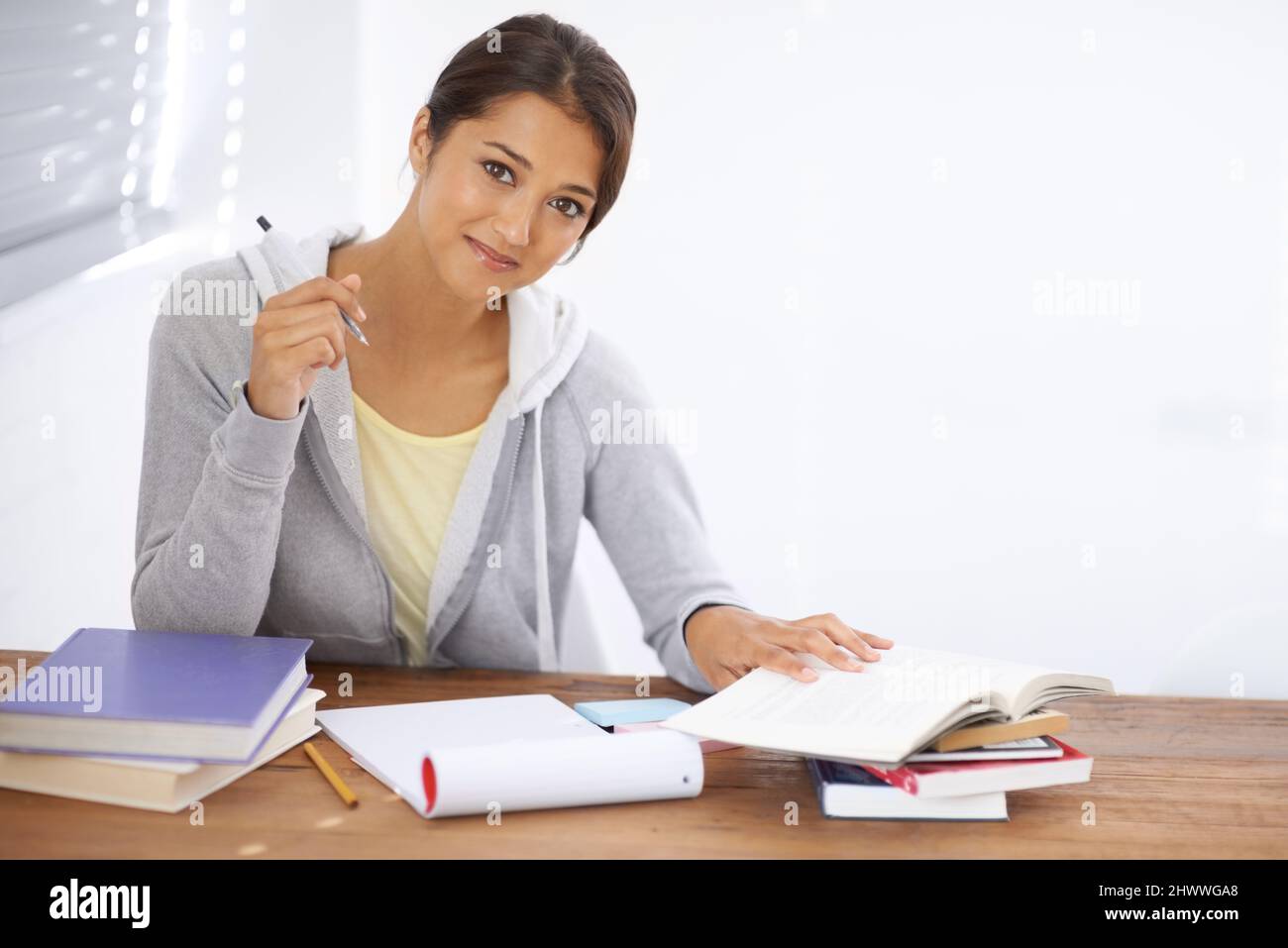 Hitting the books with a positive attitude. A pretty young university student studying for her finals in her dorm room. Stock Photo