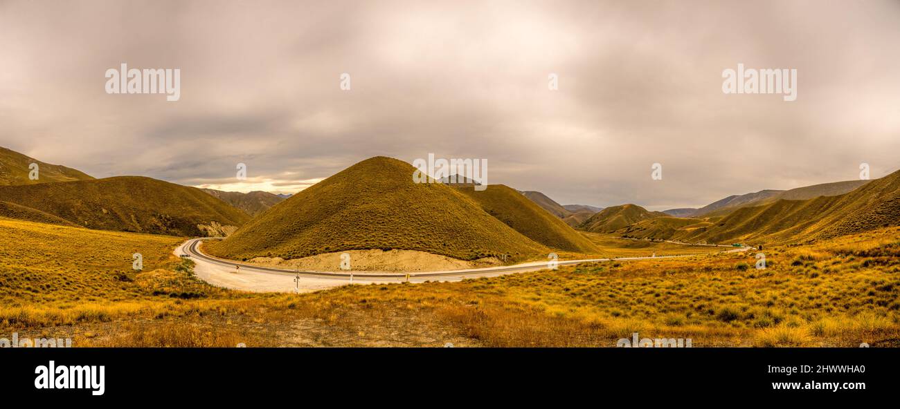 A wide panoramic view of the highway from the summit of the Lindis Pass Stock Photo