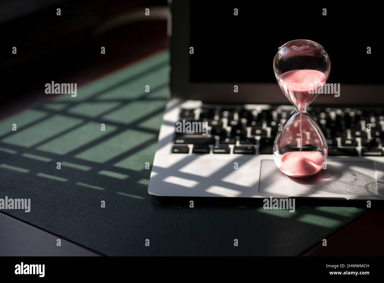 Hourglass sand timer on top of laptop. Passing time, countdown or