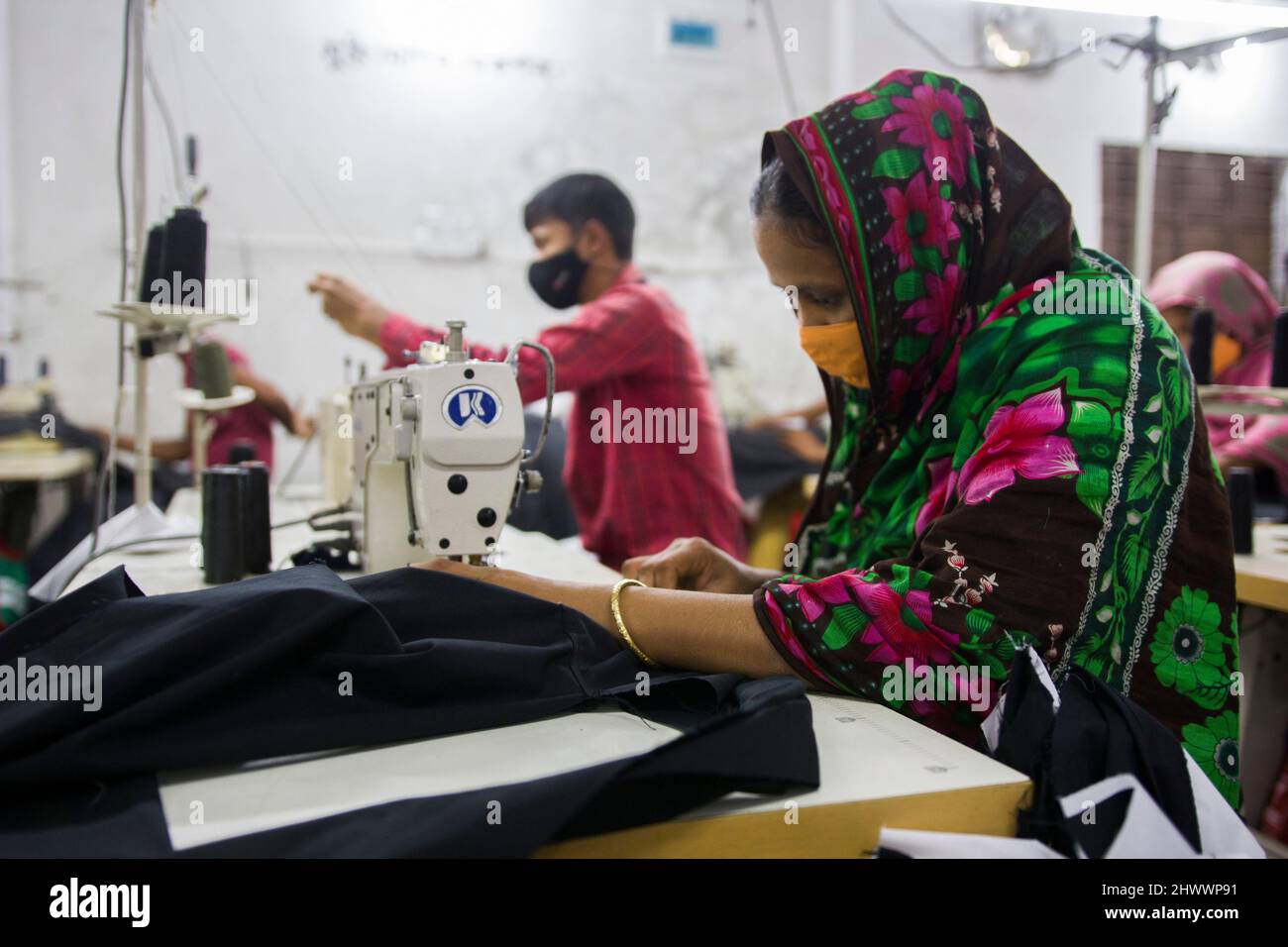 Garment workers at work on the production line inside a garment factory in Bangladesh. Stock Photo
