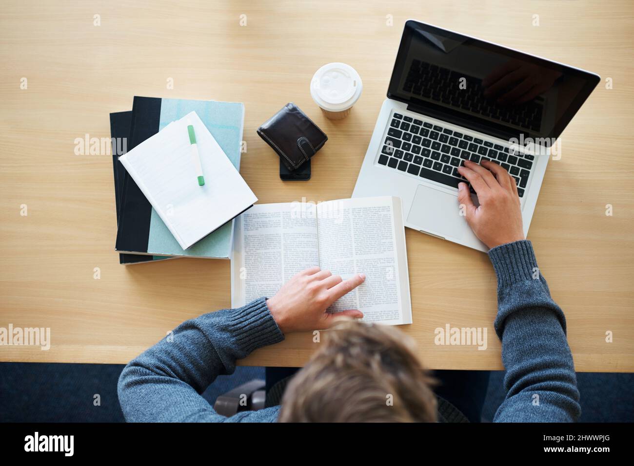 Studying in the library. A young man studying at a desk using both