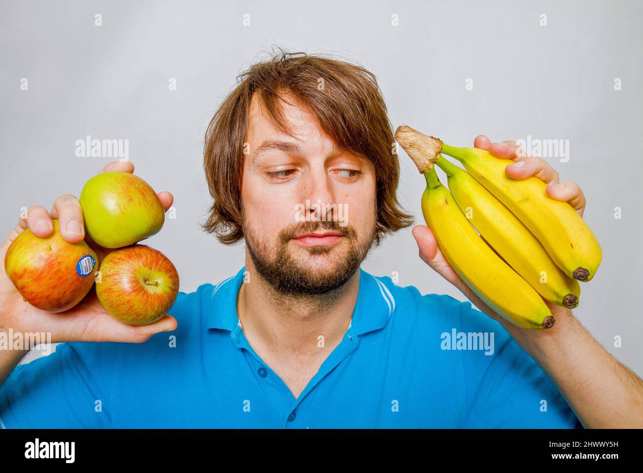 The picture shows a man deciding whether to eat an Apple or a Banana