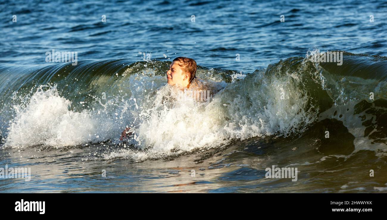 boy enjoys swimming in the waves at Dauphin Island Stock Photo