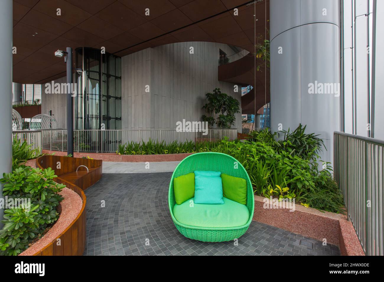 A green rattan outdoor sofa seat placement at the Oasis Garden, CapitaSpring, Singapore Stock Photo