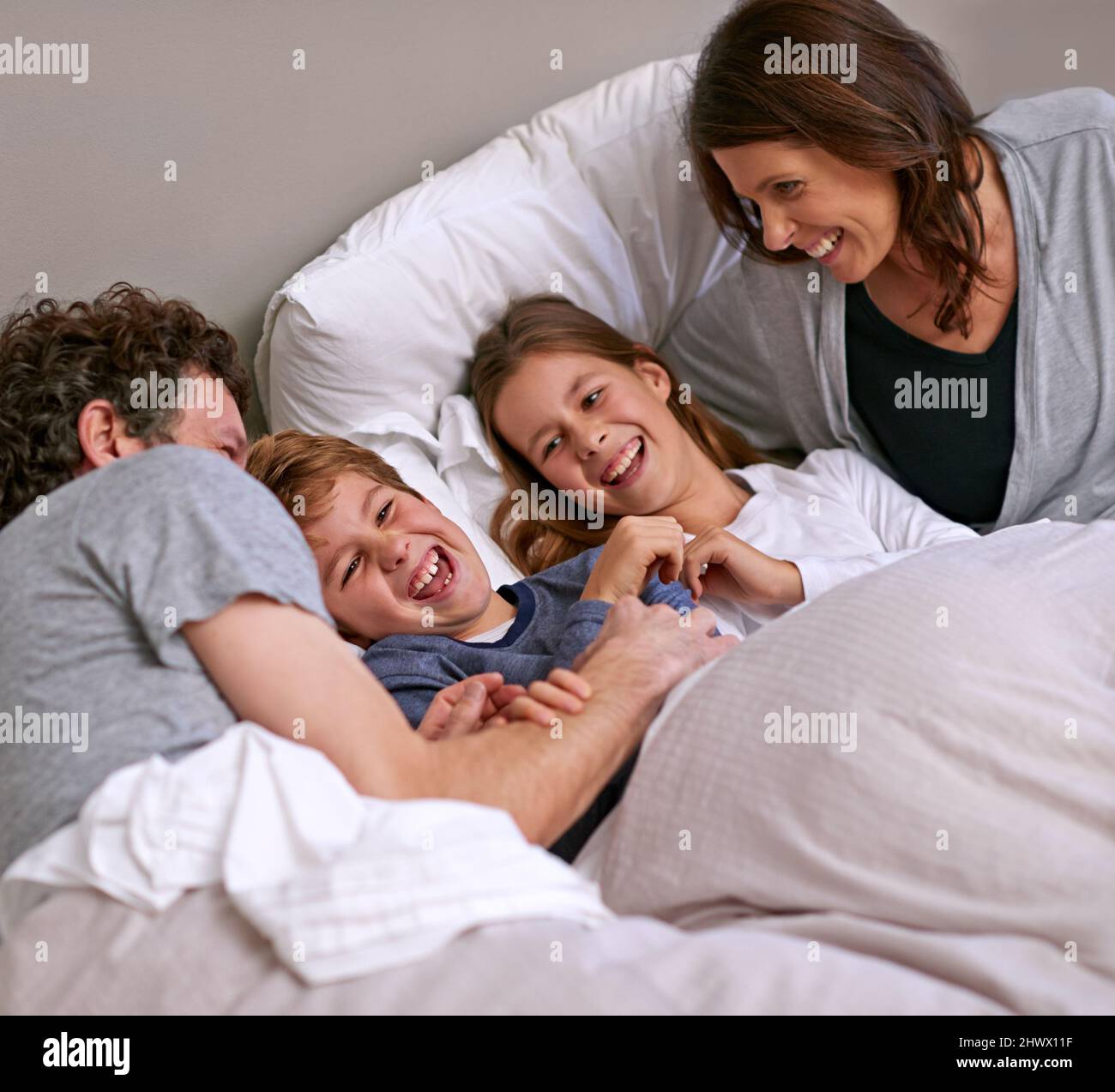Family time. Shot of a happy family of four in the bedroom. Stock Photo